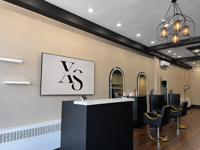 Xtreem Studio reception desk, logo wall art, black styling chairs, and geometric chandelier